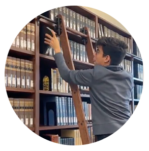 Carols climbs the library ladder to get a 研究 book from the top shelf